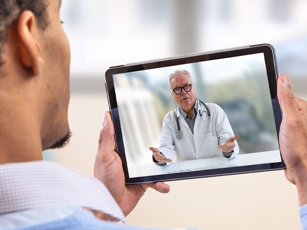 Image of a man talking to a doctor over a tablet 