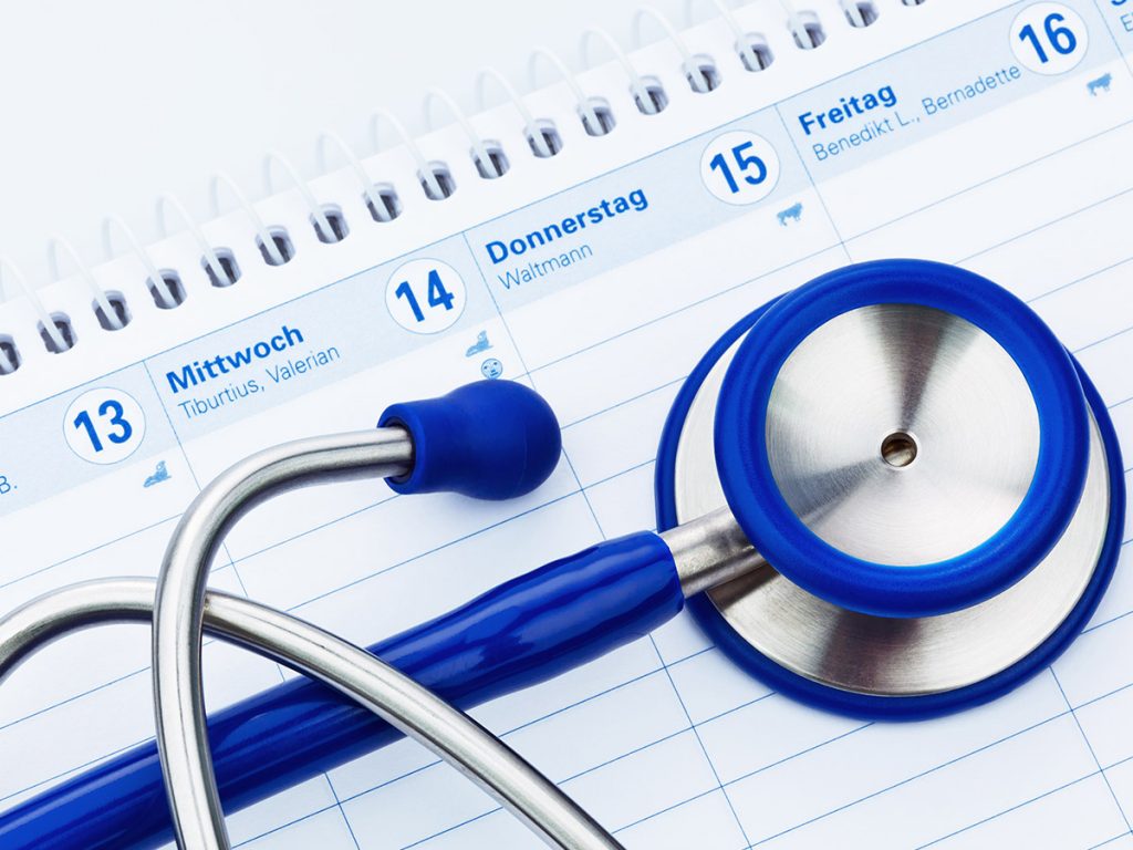 Image of a blue and silver stethoscope sitting on top of a calendar. 